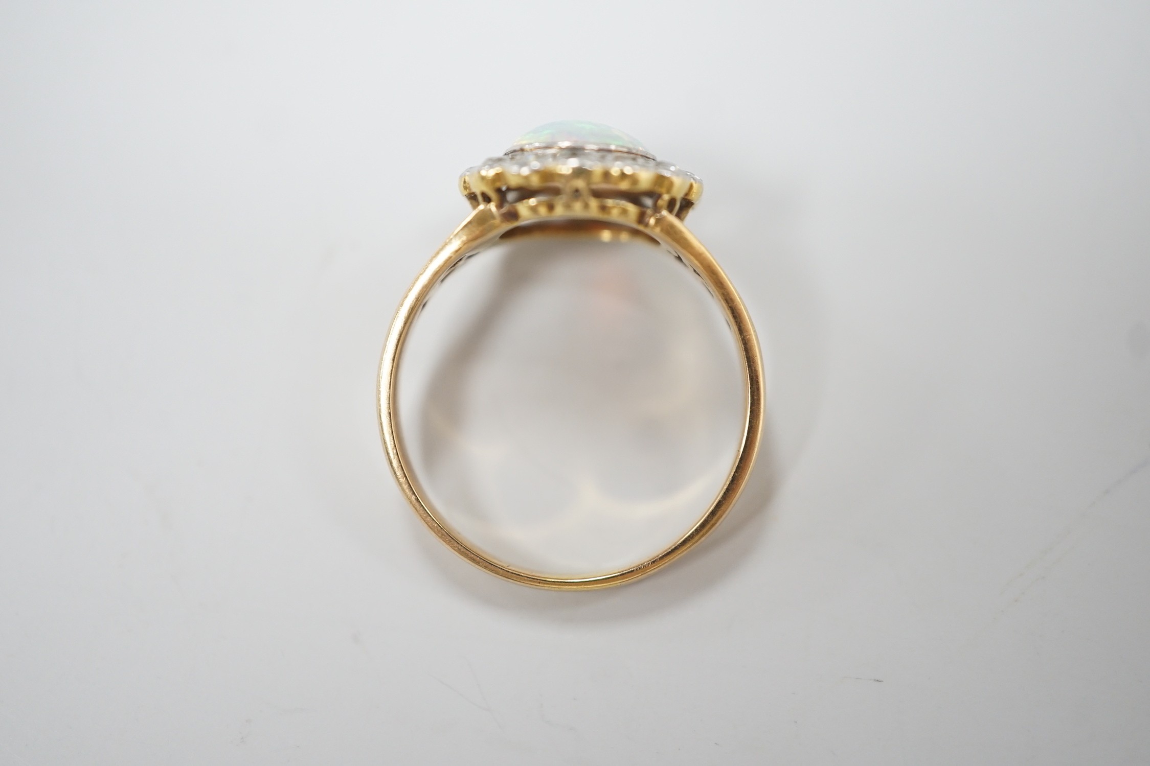 A 1920's? yellow metal, white opal and round cut diamond set circular cluster ring, size O, gross weight 3.6 grams.